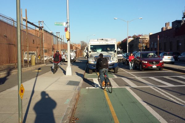 Bikes in a city swerving away from an industrial truck driving in the bike lane.